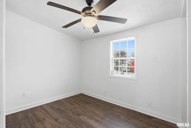 an empty room with wooden floor ceiling fan and windows