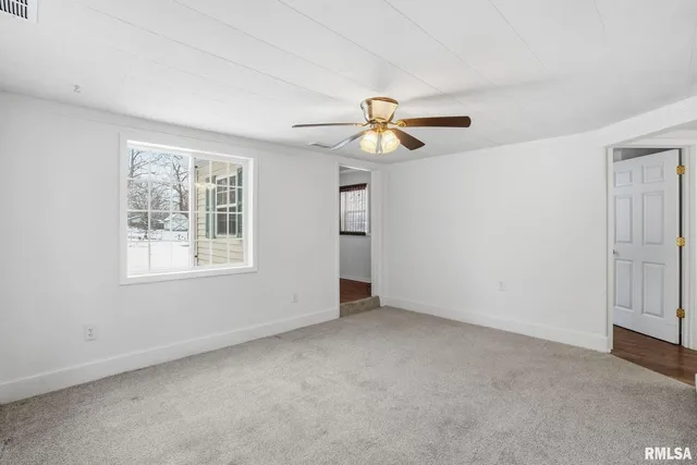 an empty room with windows and fan