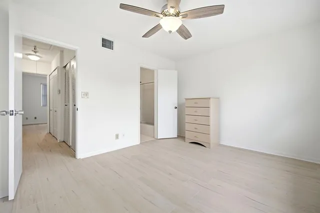 an empty room with windows and fan