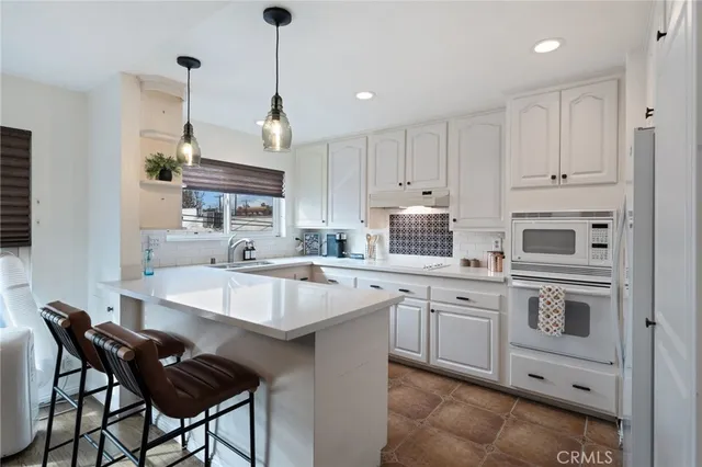 a kitchen with cabinets a sink dishwasher a stove and a dining table with wooden floor