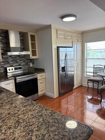 a kitchen with stainless steel appliances granite countertop a stove top oven a sink and a refrigerator