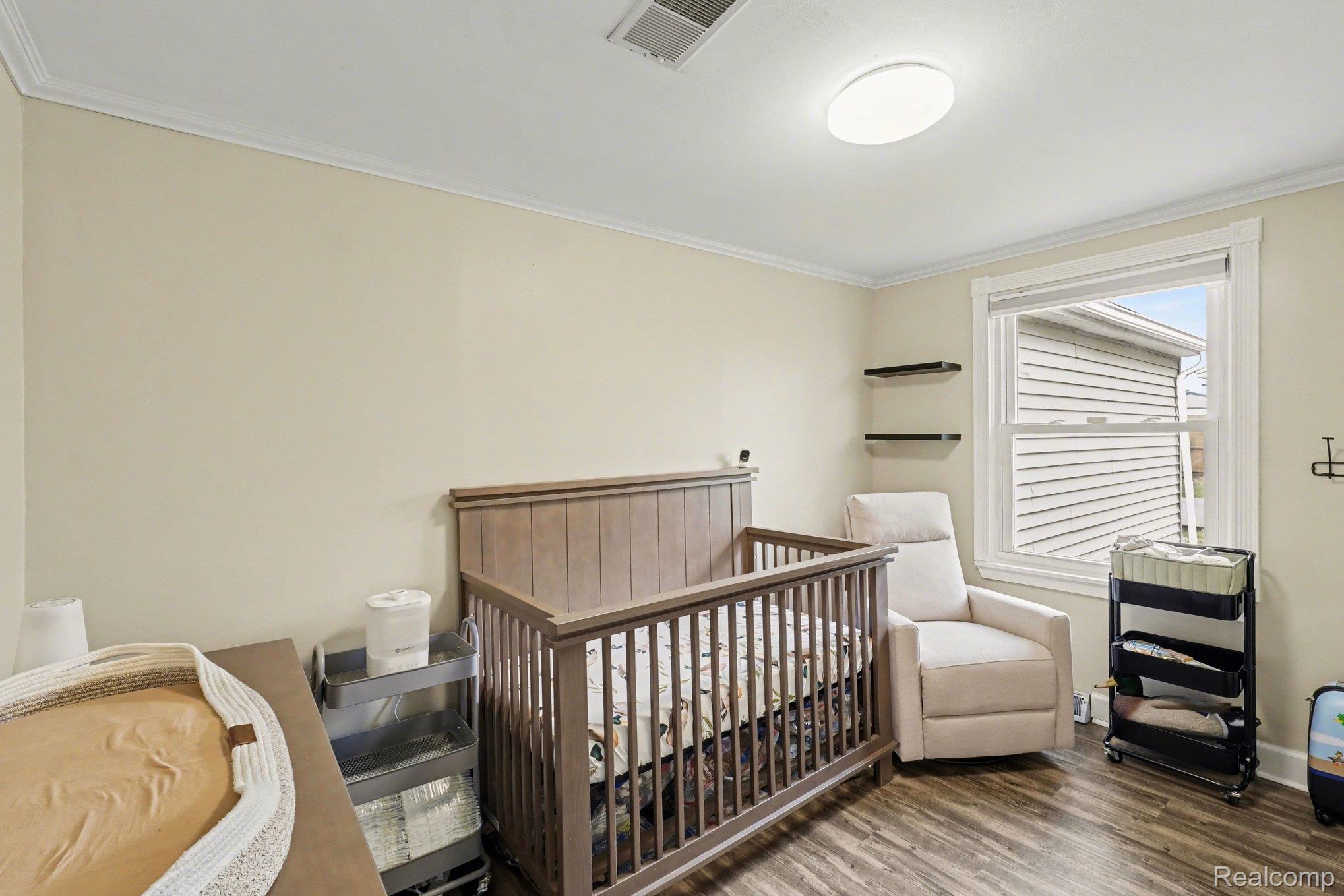16485 Jennings Road Fenton, MI 48430 - Photo 24 of 27 Bedroom with crown molding, a nursery area, and wood finished floors