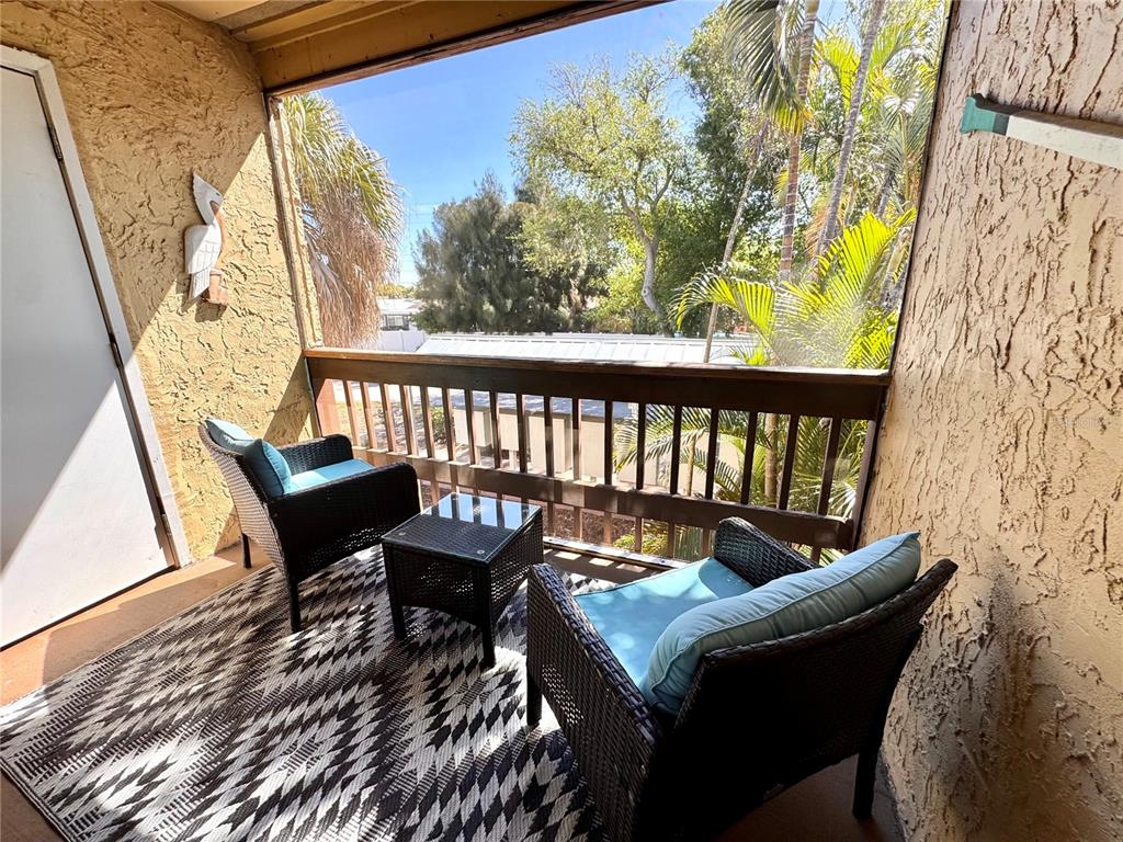 3443 Clark Road, Unit 242 Sarasota, FL 34231 - Photo 18 of 21 a balcony with wooden floor and outdoor seating
