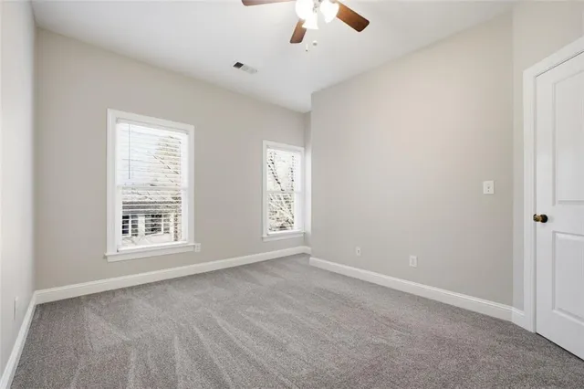 an empty room with windows and fan