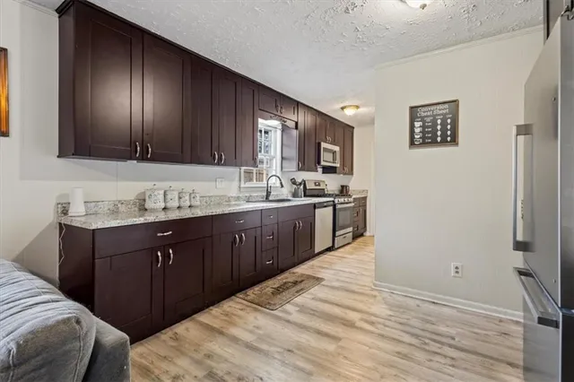 a kitchen with granite countertop stainless steel appliances a sink stove top oven and granite counter top