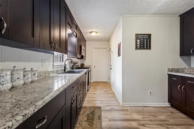 a kitchen with a sink and a stove top oven with wooden floor