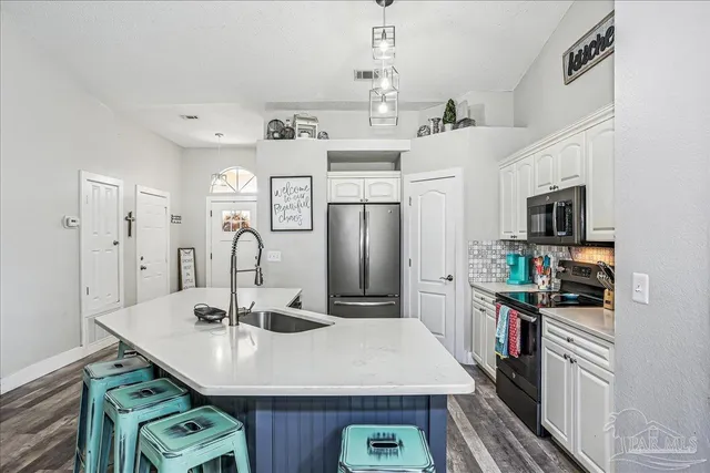 a kitchen with stainless steel appliances granite countertop a refrigerator a stove and a sink with wooden floor