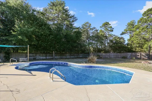 a view of a swimming pool with a patio and a yard
