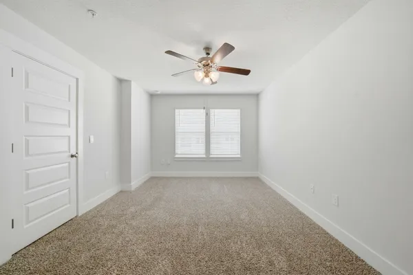 an empty room with closet and a ceiling fan