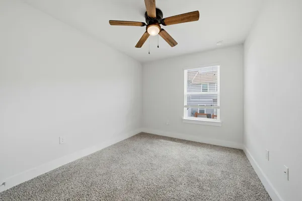 an empty room with a window and a fan