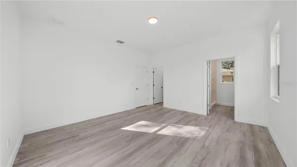 a view of empty room with wooden floor and fan