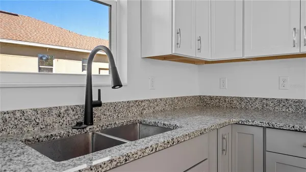 a kitchen with a refrigerator and countertop white cabinets