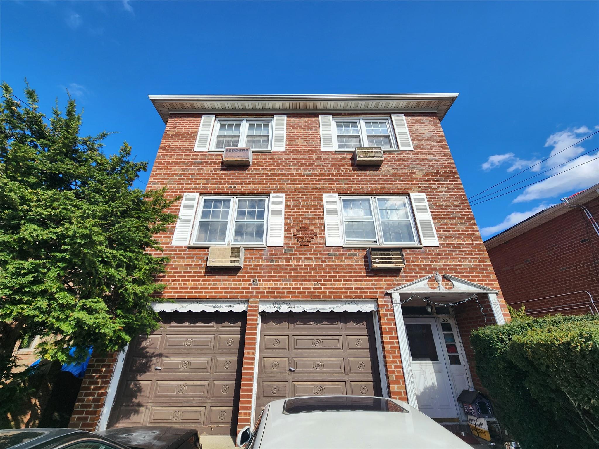 View of front facade with an attached garage, driveway, and brick siding