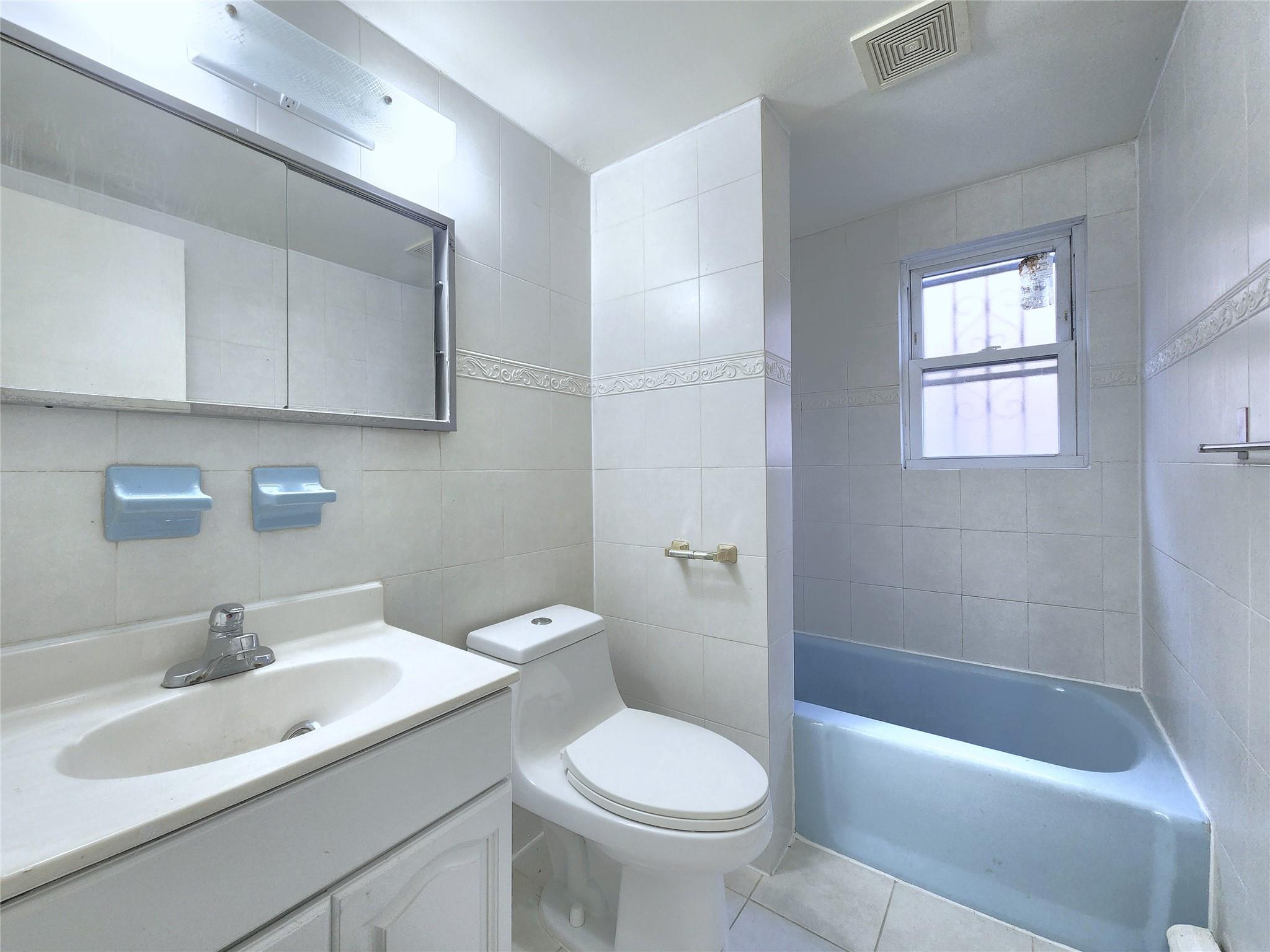 61-33 165th Street Queens, NY 11365 - Photo 11 of 11 Bathroom with vanity, a bathtub, toilet, visible vents, and tile walls