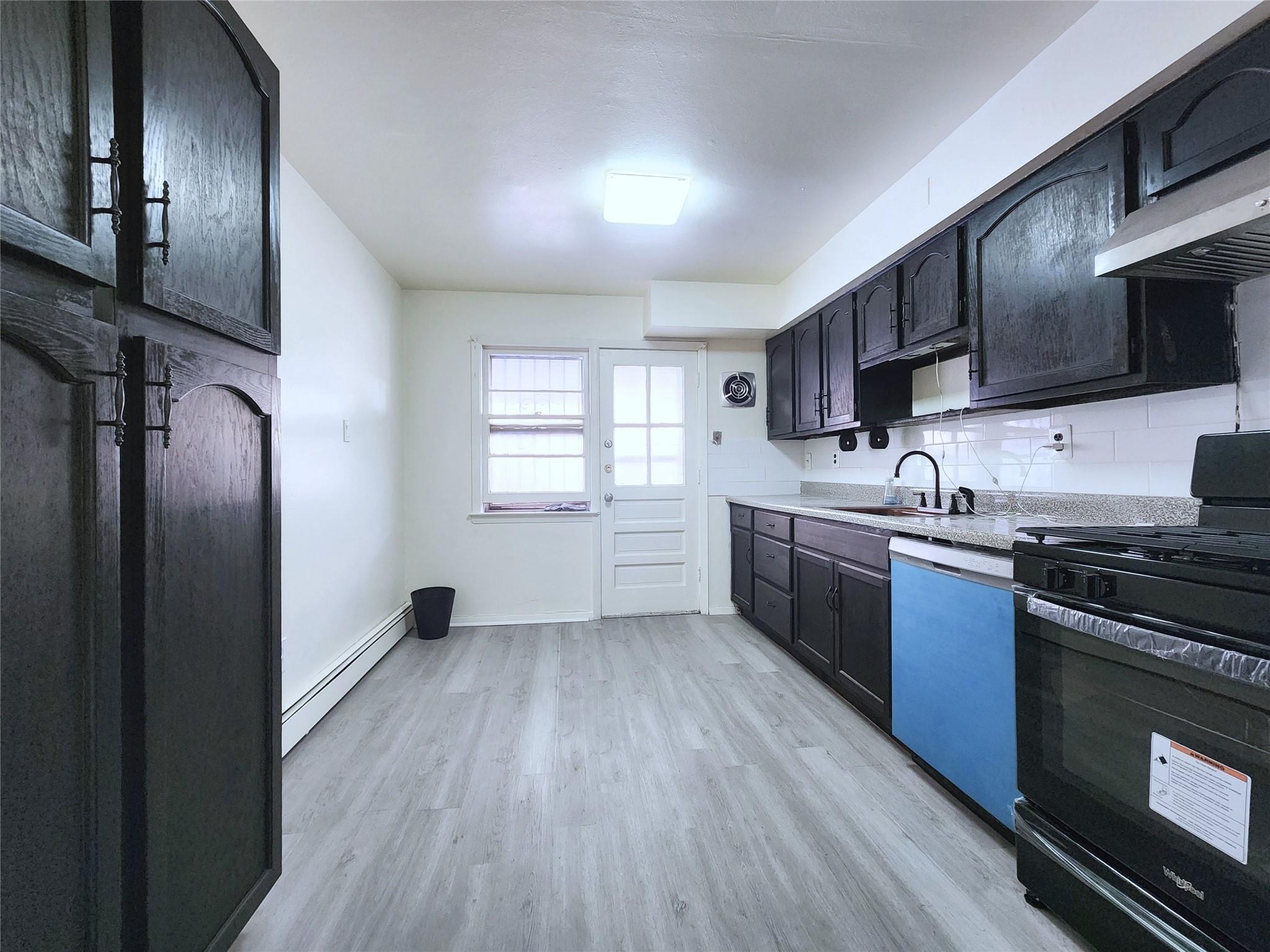 61-33 165th Street Queens, NY 11365 - Photo 3 of 11 Kitchen featuring light wood-style flooring, gas stove, a sink, dishwasher, and a baseboard radiator