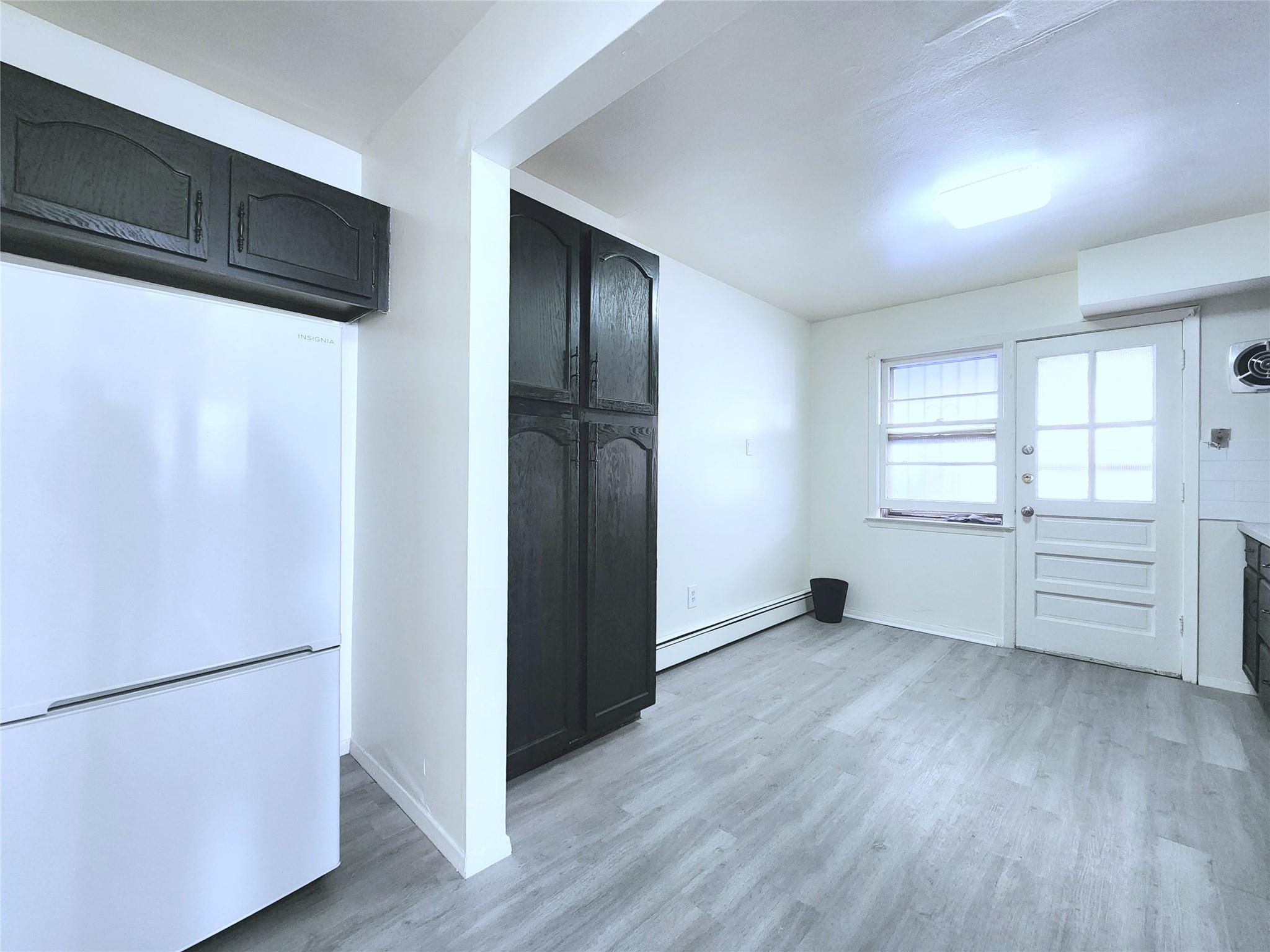 61-33 165th Street Queens, NY 11365 - Photo 4 of 11 Kitchen with light wood-style flooring, a baseboard radiator, freestanding refrigerator, and baseboards