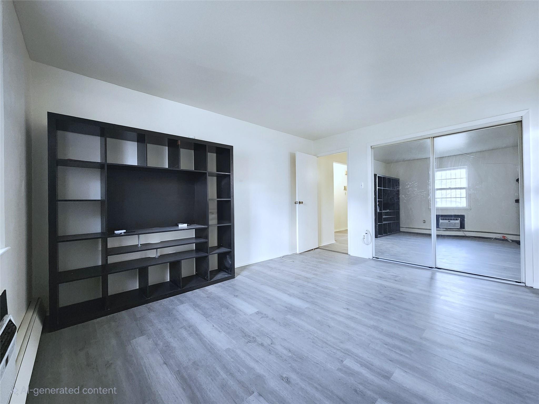 61-33 165th Street Queens, NY 11365 - Photo 8 of 11 Unfurnished living room with baseboard heating and wood finished floors