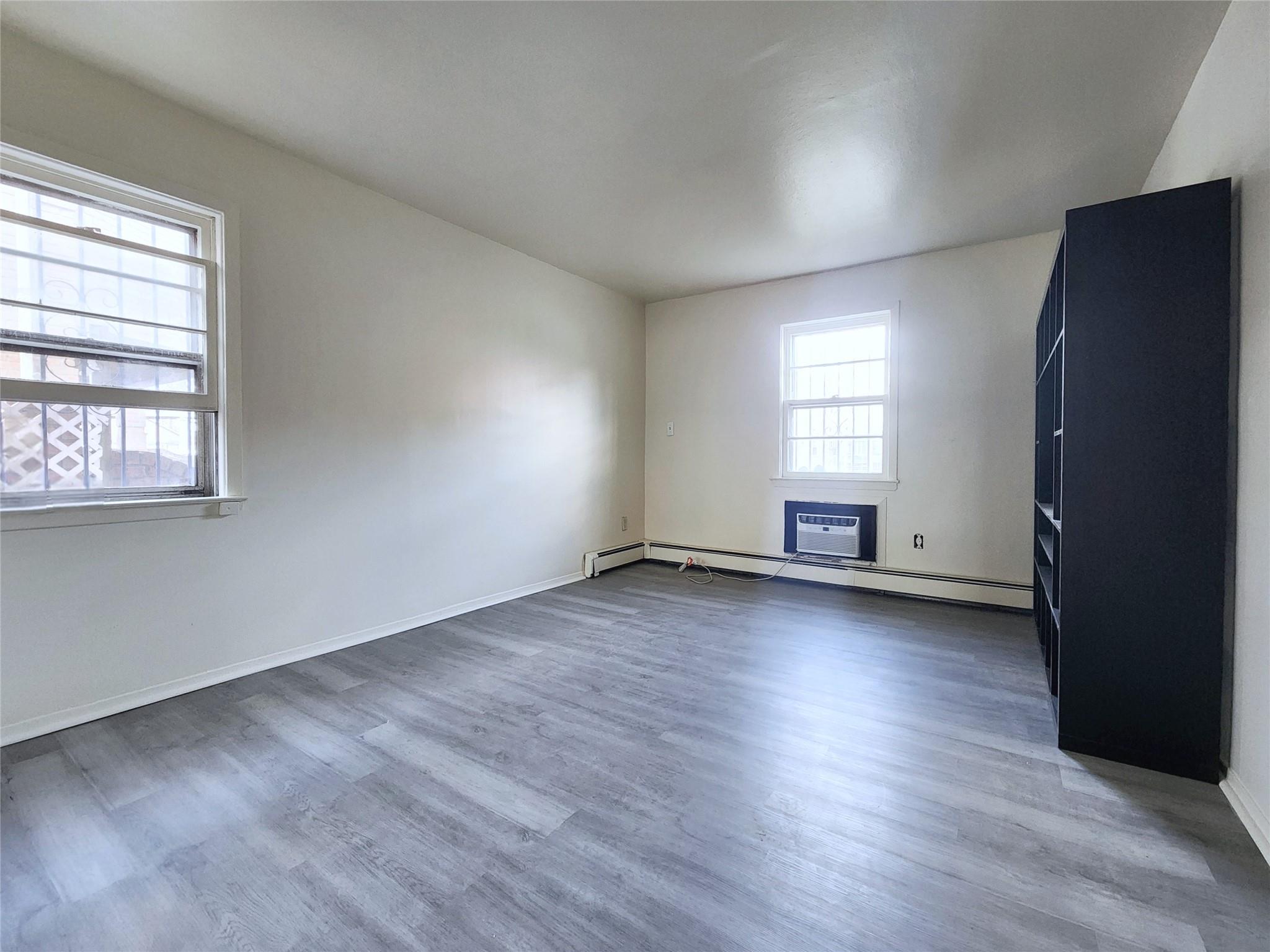 61-33 165th Street Queens, NY 11365 - Photo 9 of 11 Empty room with baseboard heating, wood finished floors, and baseboards