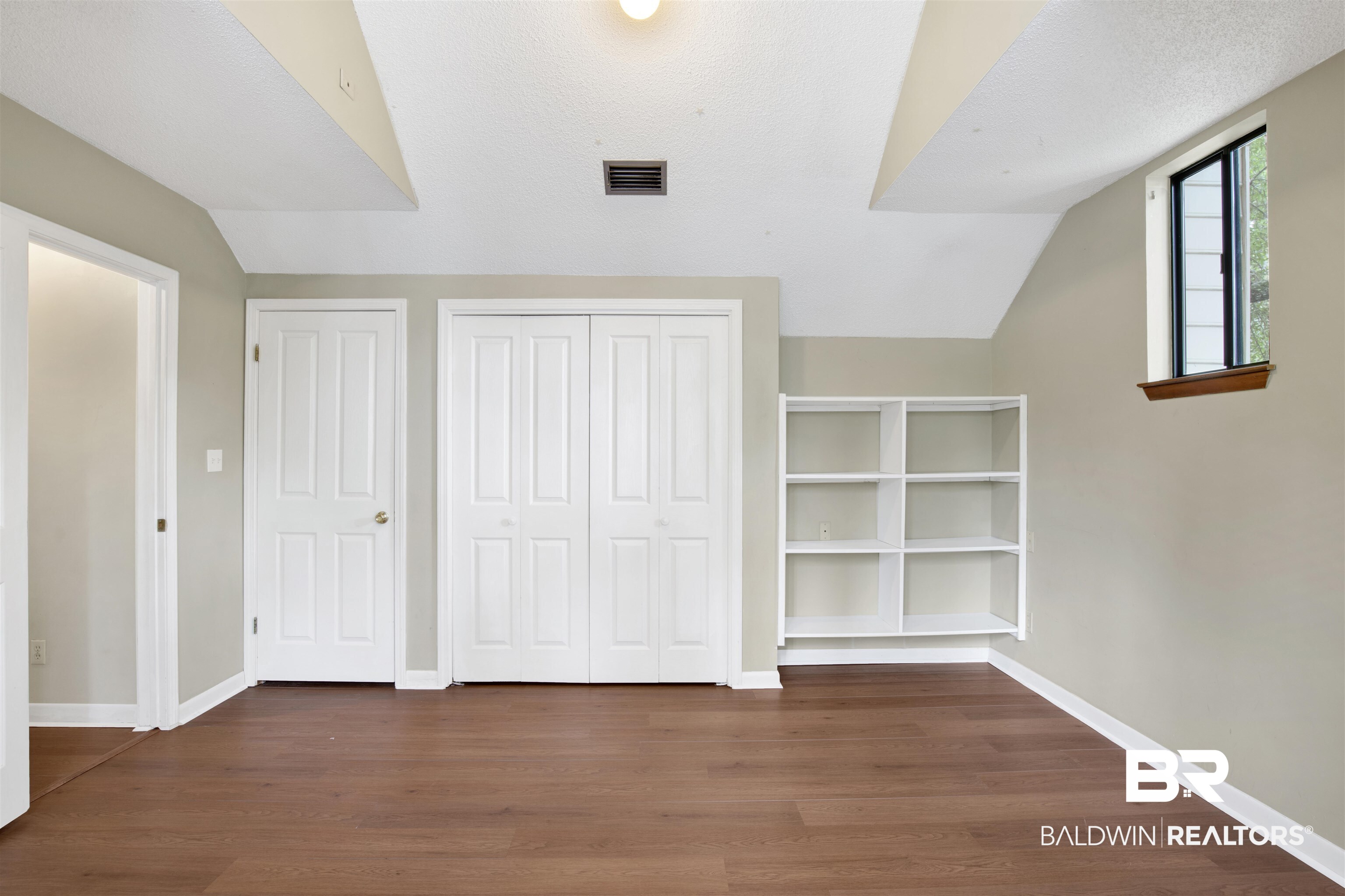 126 Montclair Loop Daphne, AL 36526 - Photo 16 of 25 Unfurnished bedroom featuring vaulted ceiling, wood finished floors, and a textured ceiling