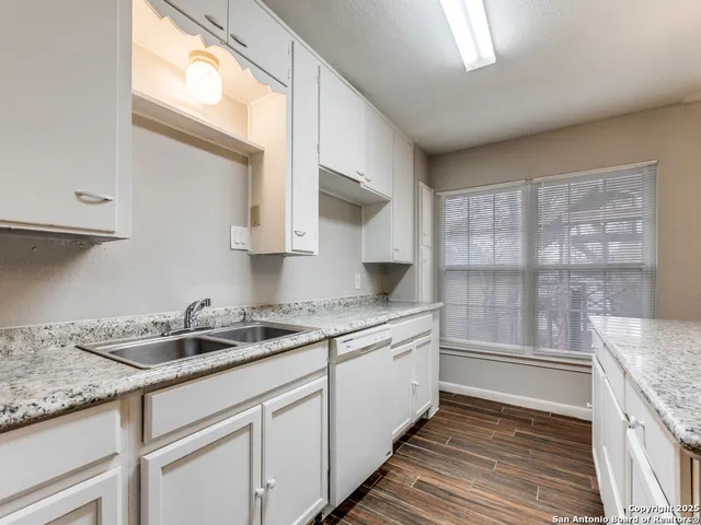 an empty room with wooden floor chandelier fan and windows