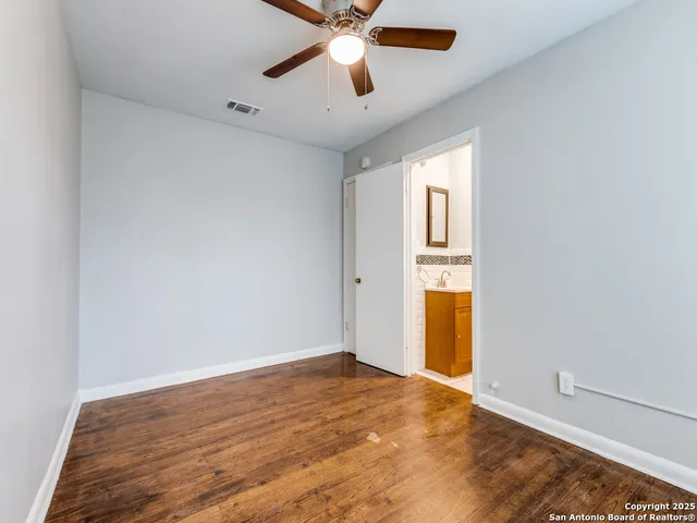 an empty room with chandelier fan and windows