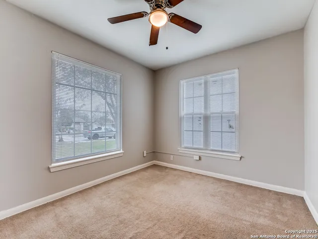an empty room with windows and fan