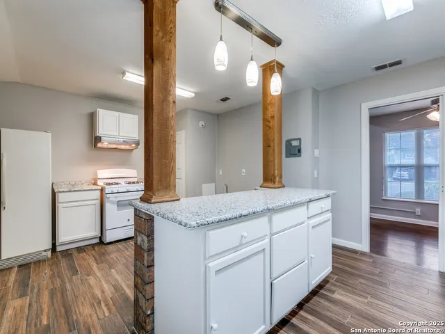 a kitchen with wooden floors and white cabinets