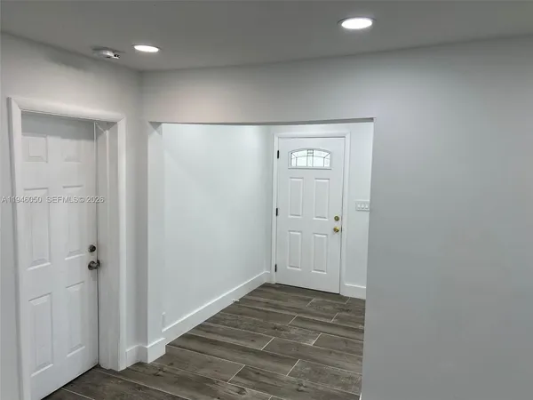 a view of a hallway with wooden floor and chandelier fan