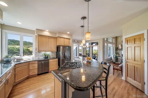 a kitchen with stainless steel appliances granite countertop table chairs and wooden floor