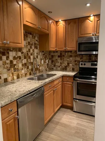 a kitchen with stainless steel appliances granite countertop a stove a sink and a microwave