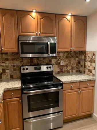 a kitchen with granite countertop a stove and a microwave