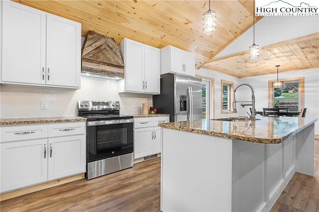 a kitchen with stainless steel appliances granite countertop a sink a stove and refrigerator