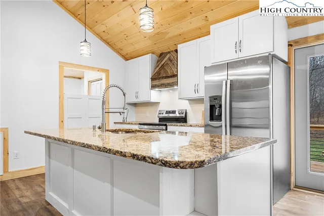 a kitchen with kitchen island granite countertop a sink stainless steel appliances and cabinets
