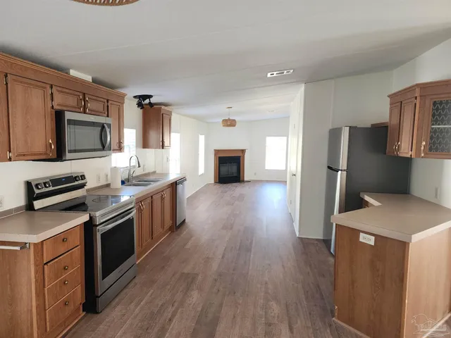 a kitchen with granite countertop a stove top oven a sink dishwasher and a refrigerator with wooden floor