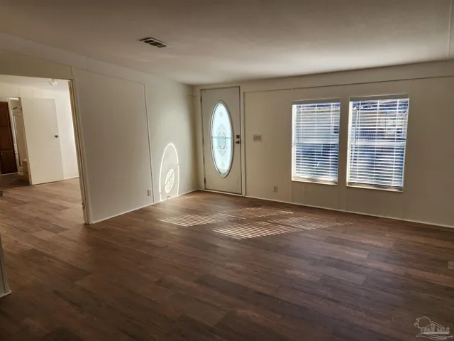 an empty room with wooden floor and windows