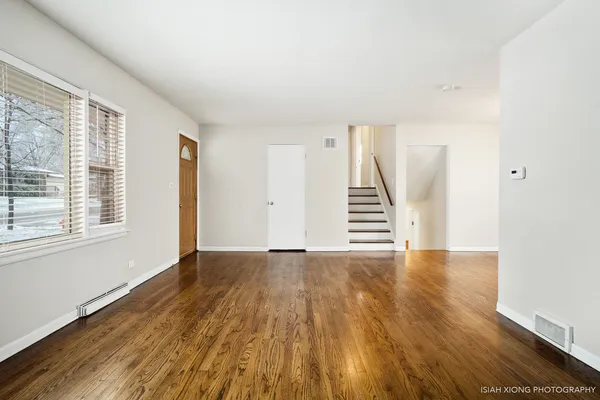 a view of an empty room with wooden floor and stairs