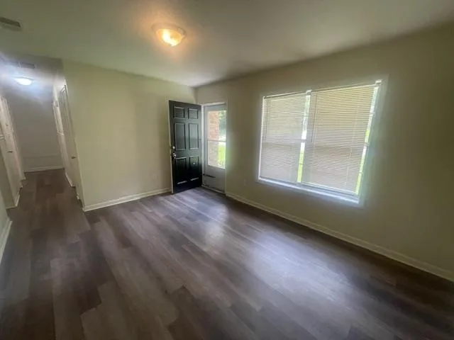 an empty room with wooden floor and windows