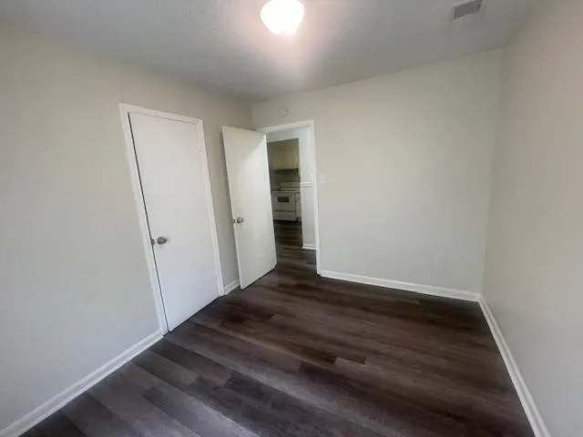 an empty room with wooden floor and entrance