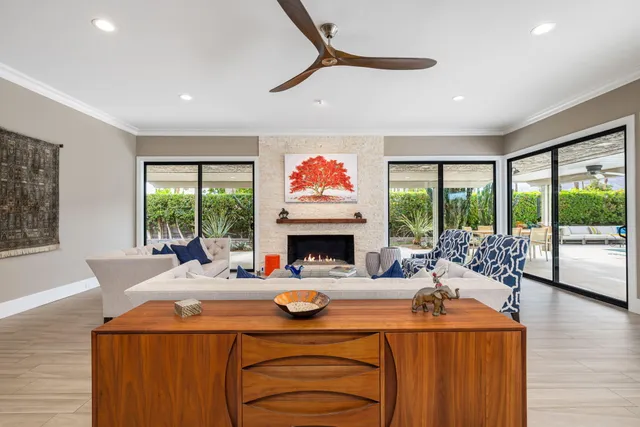 a living room with fireplace furniture large windows and a flat screen tv