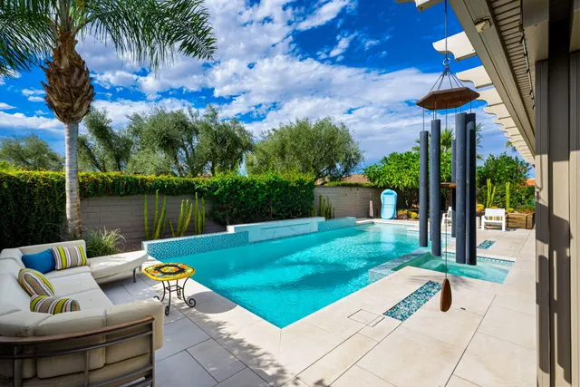 a view of a patio with couches table and chairs under an umbrella with palm trees