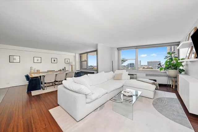 a living room with furniture and a dining table with wooden floor
