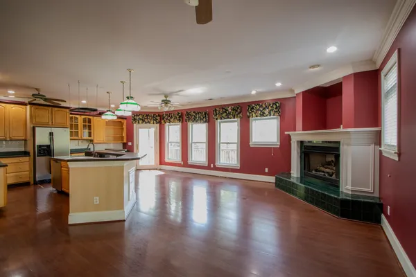a view of a livingroom with furniture hardwood floor ceiling fan and windows