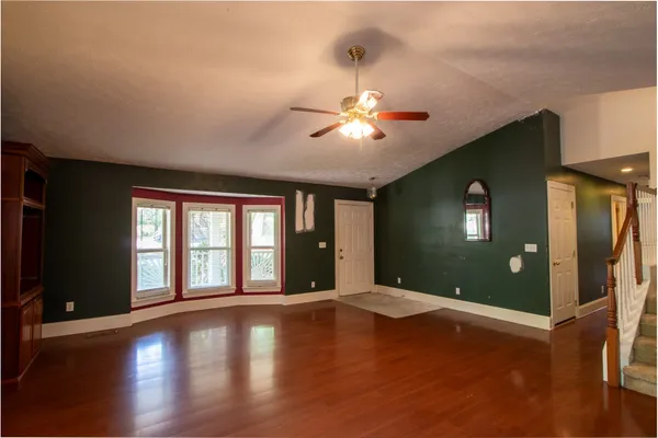 an empty room with windows and chandelier fan