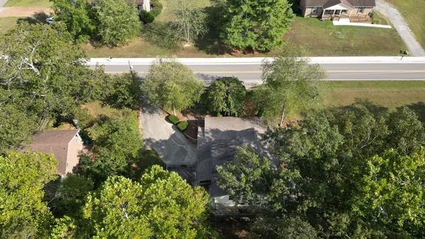 a view of a house with a yard and large trees