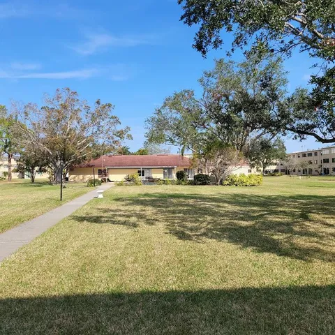 a view of a brick house next to a yard with big trees