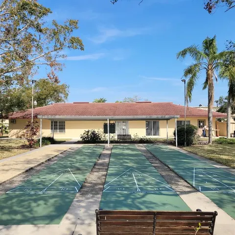 a view of a swimming pool with a lawn chairs under palm trees