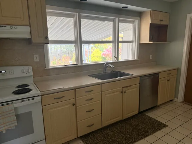 a kitchen with white cabinets window and sink