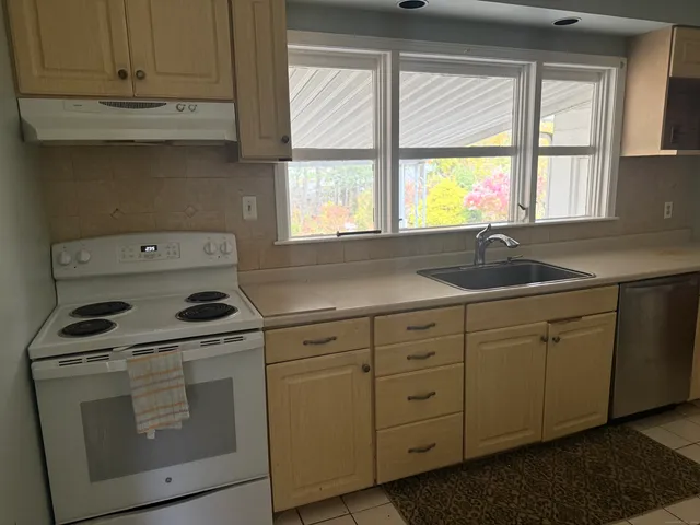 a kitchen with cabinets appliances a sink and a window