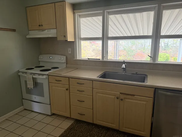 a kitchen with cabinets appliances a sink and a window