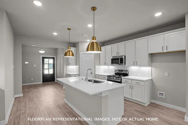 a kitchen with stainless steel appliances kitchen island granite countertop a refrigerator oven a sink dishwasher and white cabinets with wooden floor